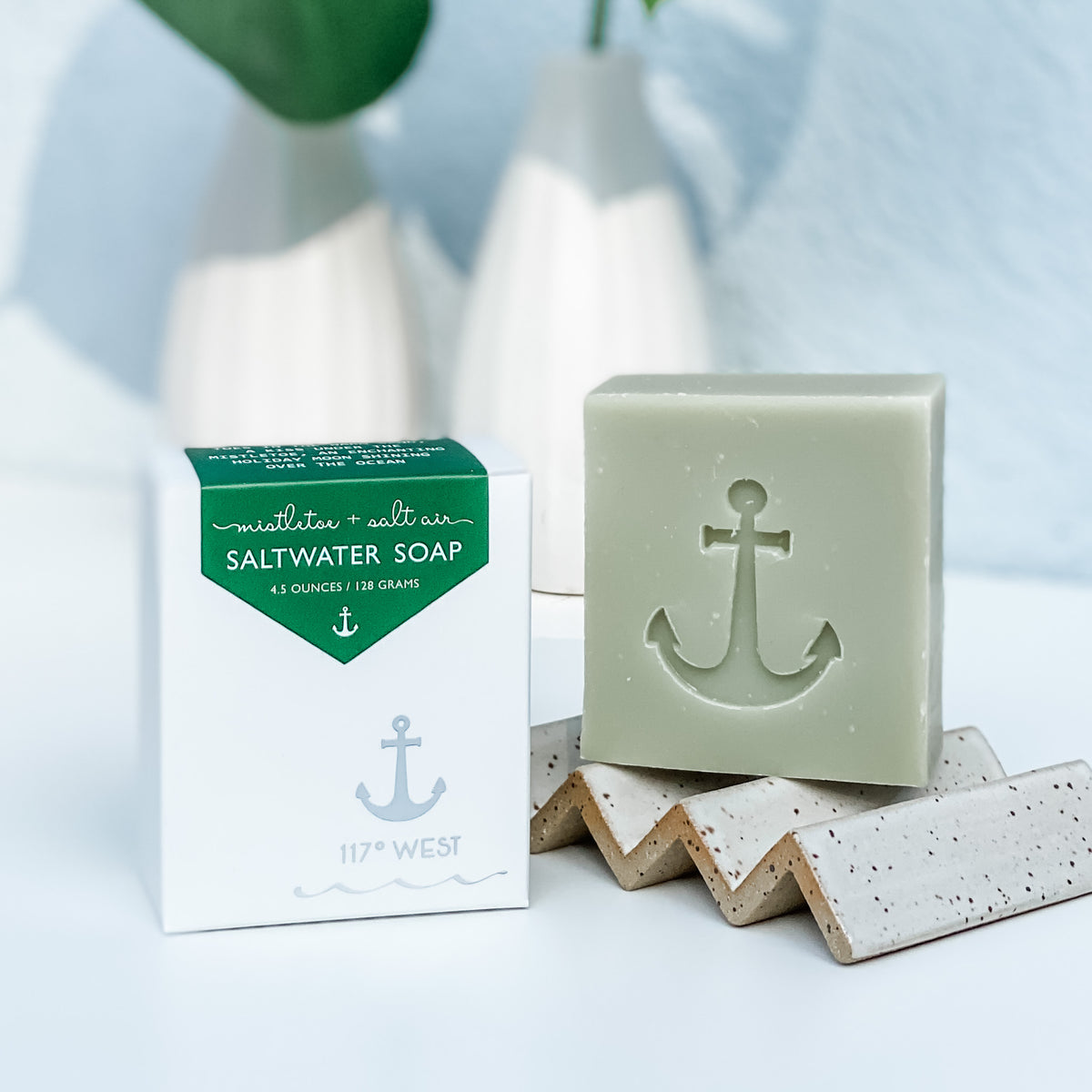 mistletoe + salt air saltwater soap pictured with a ceramic soap dish and a white background
