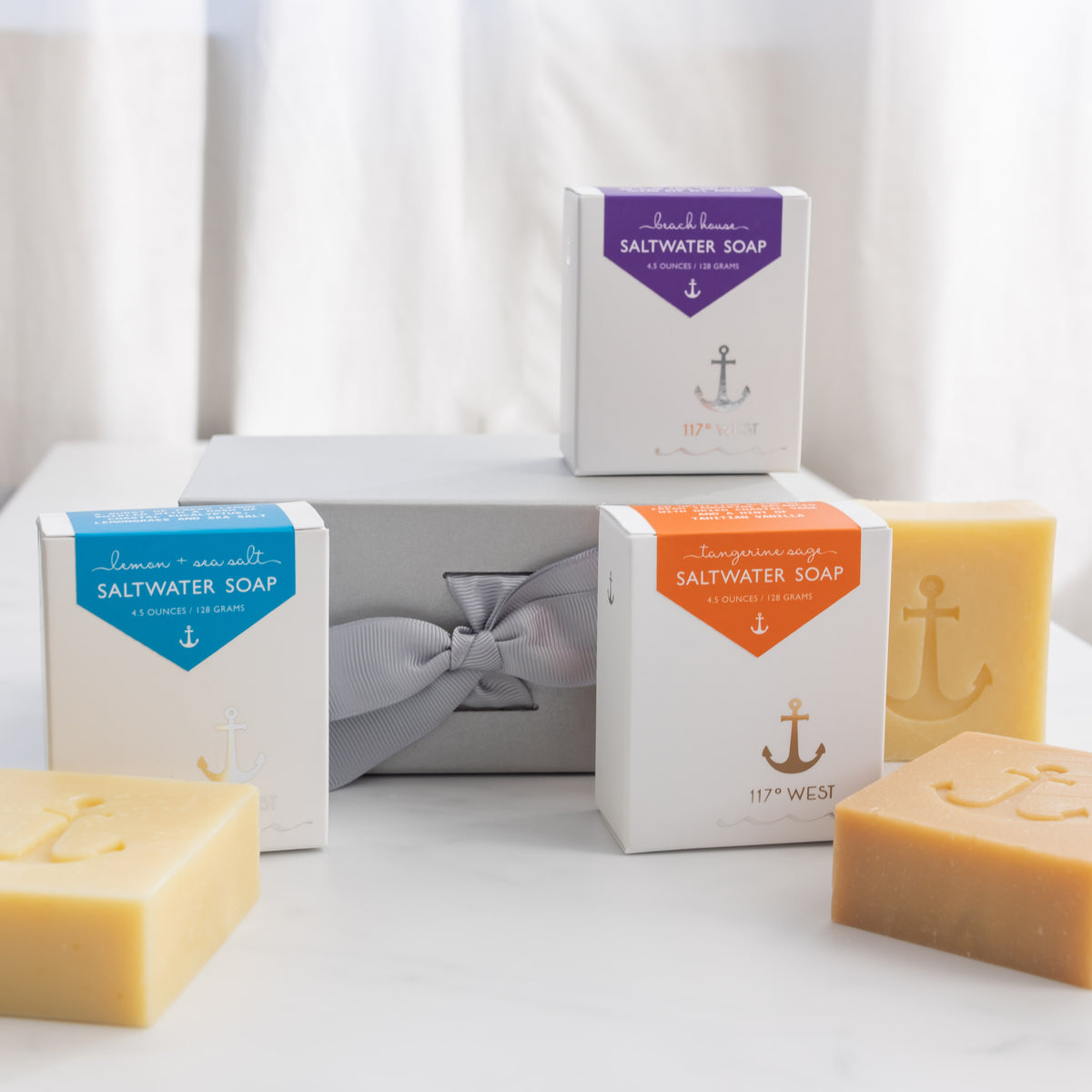 arrangement of three boxed saltwater soaps and three unboxed saltwater soaps with a gift box in the background
