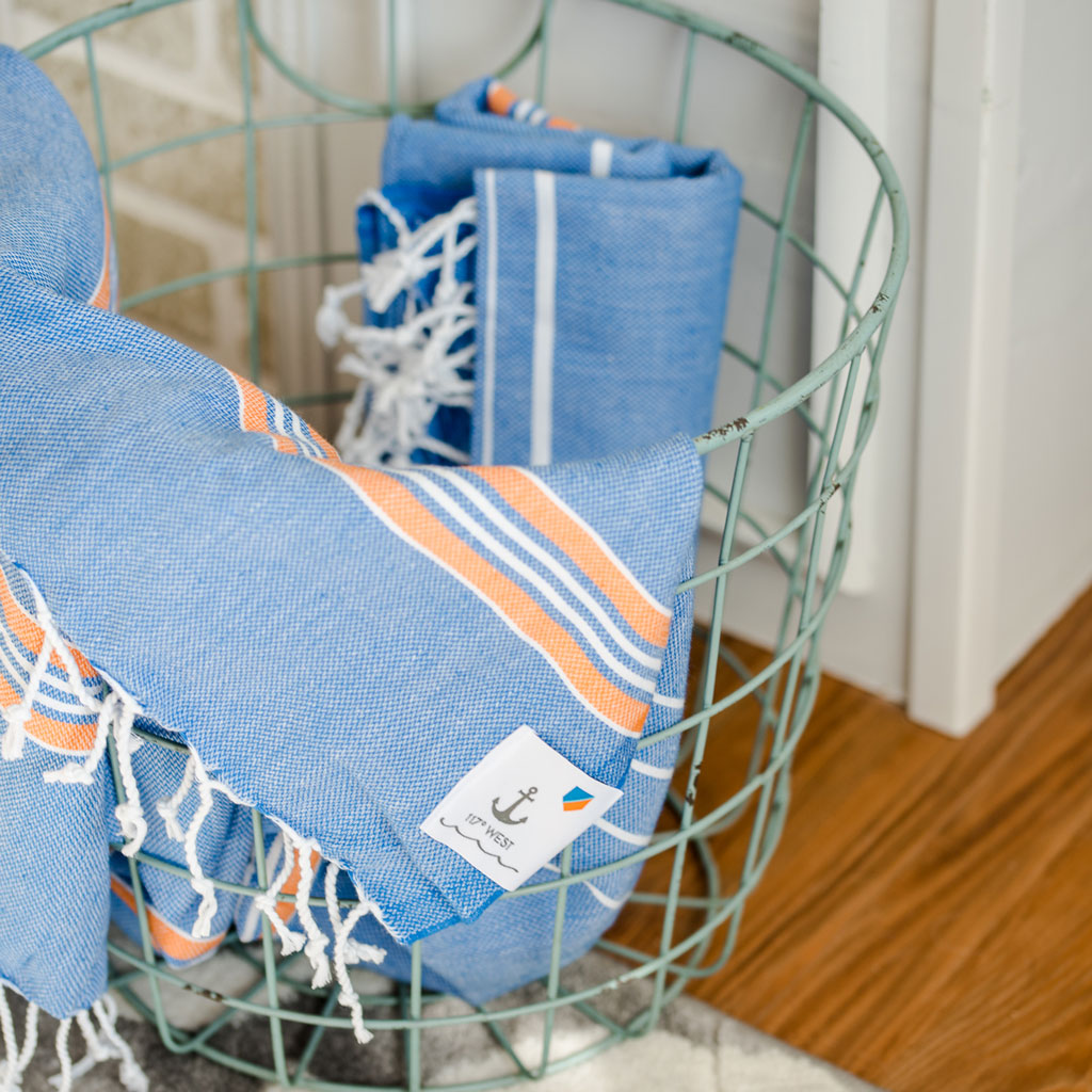 two beach turkish towels in a teal wired basket